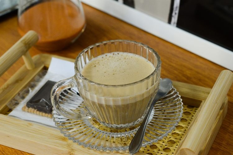 Uma xícara de café servida sobre uma bandeja de palhinha.